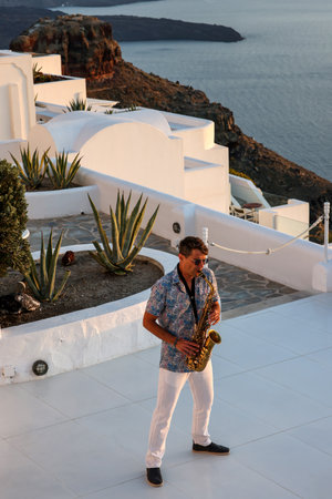 Imerovigli, Santorini, Greece - June 29, 2021: A saxophonist's concert by the light of the setting sun in Imerovigli, Santoriniのeditorial素材