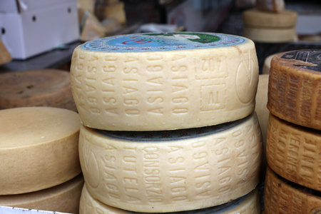 Cremona, Italy - September 7, 2022: Whole wheels of Asiago cheese sold at a street stall during the farmers market in Cremona, Lombardy, Italyのeditorial素材