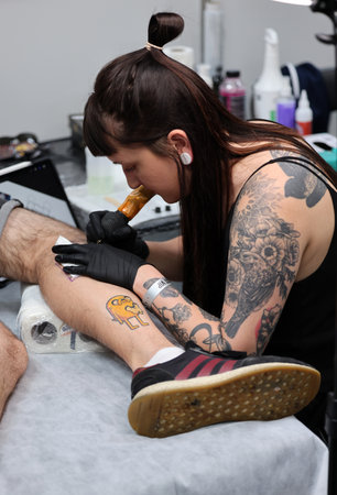 Krakow, Poland - June 12, 2022: Unidentified participant at 15th Tattoofest Convention in Cracow. Tattoo artist at work.のeditorial素材