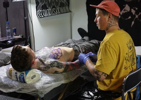 Krakow, Poland - June 12, 2022: Unidentified participant at 15th Tattoofest Convention in Cracow. One of the most prestigious tattoo festivals. Tattoo artist at work.のeditorial素材