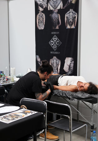 Krakow, Poland - June 12, 2022: Unidentified participant at 15th Tattoofest Convention in Cracow. One of the most prestigious tattoo festivals. Tattoo artist at work.のeditorial素材