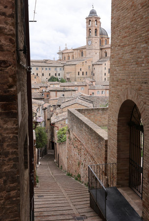A narrow, steep street with a beautiful view of Urbino. Marche, Italyの写真素材