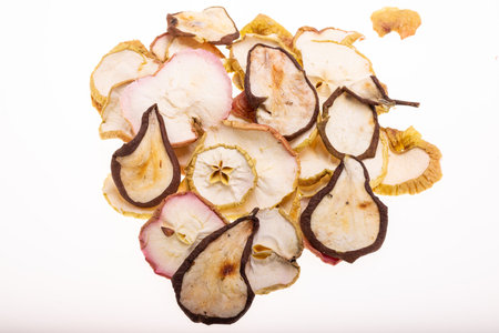 Closeup of a pile of dried slices of pears and apples isolated on a white background. Healthy raw vegetarian eat from thin fruit chips of sweet and sour flavorの写真素材