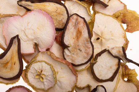 Closeup of a pile of dried slices of pears and apples isolated on a white background. Healthy raw vegetarian eat from thin fruit chips of sweet and sour flavorの写真素材