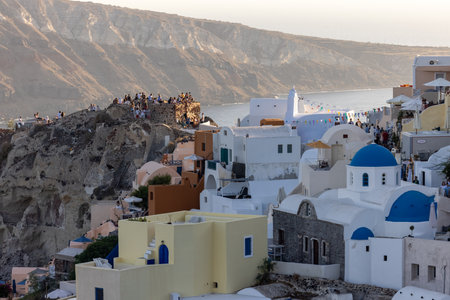 Oia, Santorini, Greece - June 28, 2021: Whitewashed buildings and the ruins of Castle of Agios Nikolaos on the edge of the caldera cliff, Oia village, Santorini, Greeceの写真素材