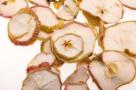 Closeup of a pile of dried apple slices isolated on a white background. Healthy raw vegetarian eat from thin fruit chips of sweet and sour flavorの写真素材