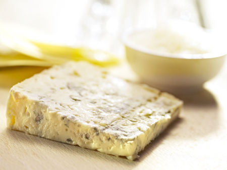 blue cheese served on a wooden board with some bowls in the backgroundの写真素材