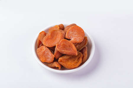 A round plate of red dried apricots on whiteの写真素材