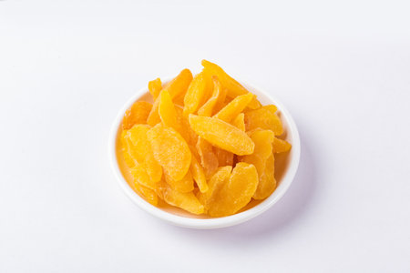 Golden dried plums on a disc on white backgroundの写真素材
