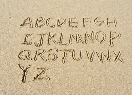 alphabet letters handwritten in sand on beach の写真素材