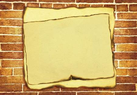 old burnt paper with burnt edges over grunge brick wall background の写真素材