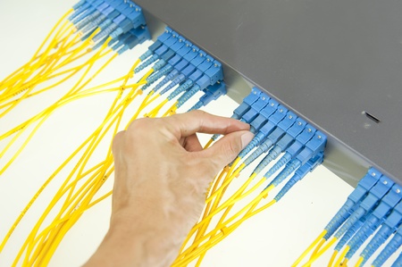 man working in network server room with fiber optic hub for digital communications and internet の写真素材