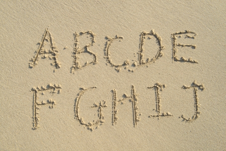 alphabet letters handwritten in sand on beachの写真素材