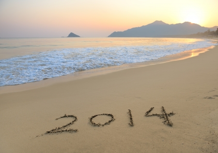 Year 2014 hand written on the white sand in front of the seaの写真素材