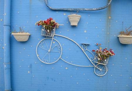 Beautiful decorative bicycle on wall with pots of flowersの写真素材