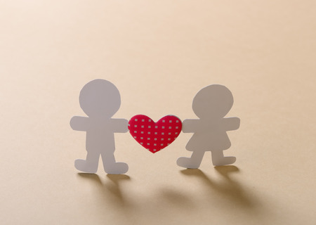 Silhouettes of men, women and heart cut out of paper on a wooden backgroundの写真素材