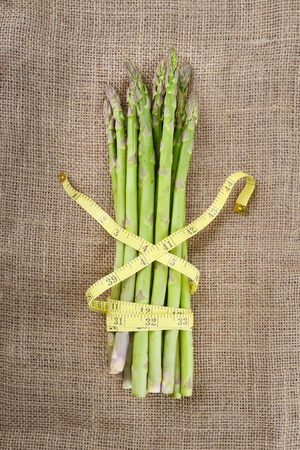 bunch of green asparagus with tape measureの写真素材