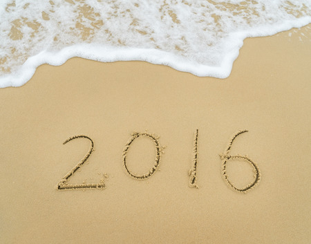 Year 2016 written on the white sand in front of the seaの写真素材
