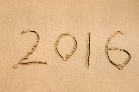 Year 2016 hand written on the white sand in front of the seaの写真素材