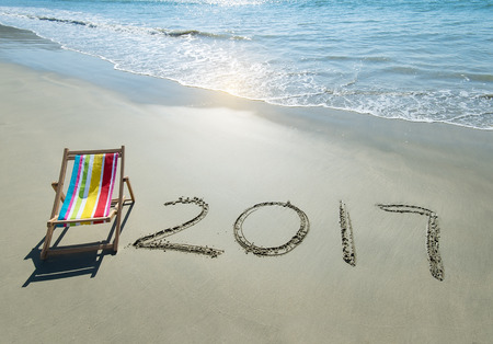 2017 written in sand write on tropical beach with Deck chair.
