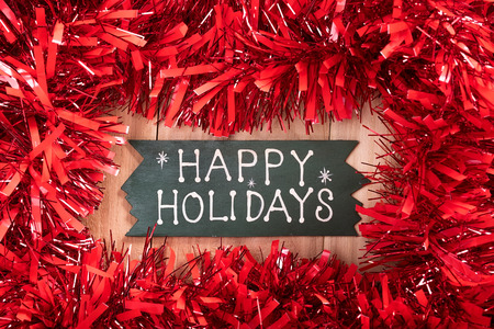 happy holidays text and Christmas decorations on a wooden backgroundの写真素材
