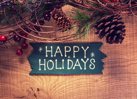 happy holidays text and Christmas decorations on a wooden backgroundの写真素材
