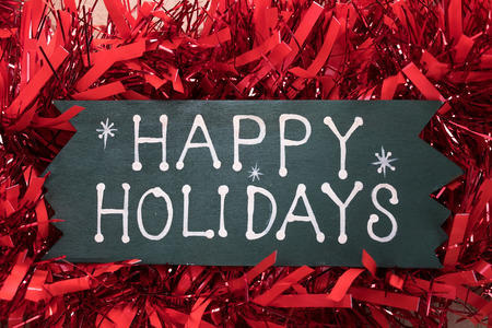 happy holidays text and Christmas decorations on a wooden backgroundの写真素材