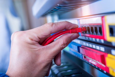 administrator holding network cables connected to serversの写真素材