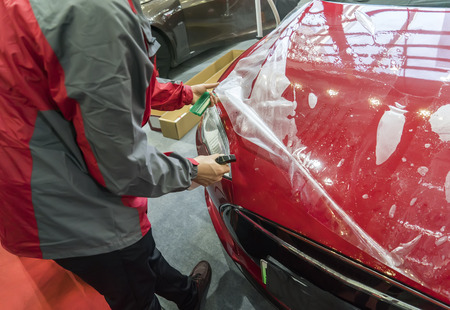 Worker applying car  protective film with spatulaの写真素材