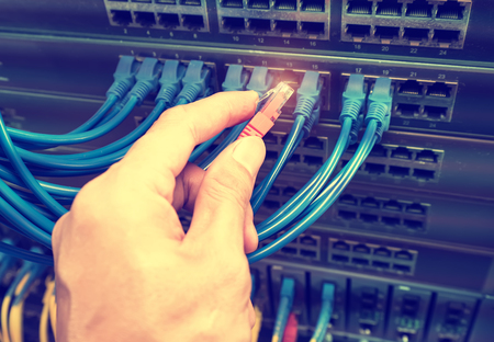 man working in network server room with hub for digital communications and internet