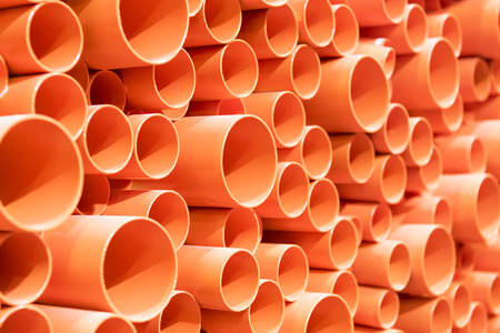 orange PVC pipes stacked in construction siteの写真素材