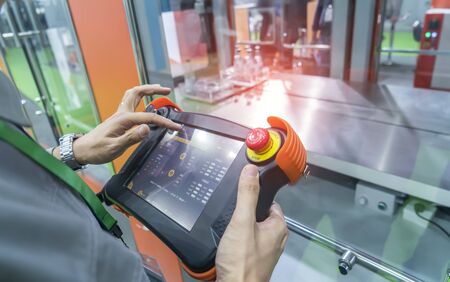 worker holding smart panel to control automatic robot in ai factory