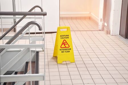 Yellow Caution wet floor sign on wet floor with Germany and English Languageの写真素材