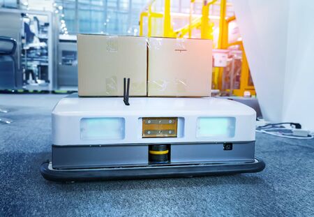 warehouse robot car carries cardboard box assembly in factoryの写真素材