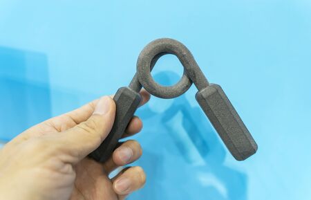 hand with fitness hand gripper printed on 3d printer close-up.