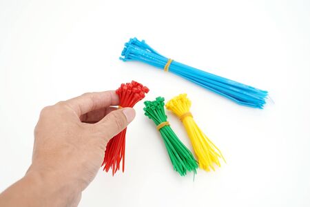 hand with different colors of plastic nylon cable ties closeup on white background  