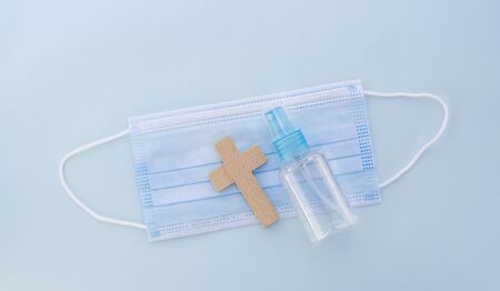 vintage wooden cross with medical mask and hand sanitizer bottle . Prayer for healing sick concept