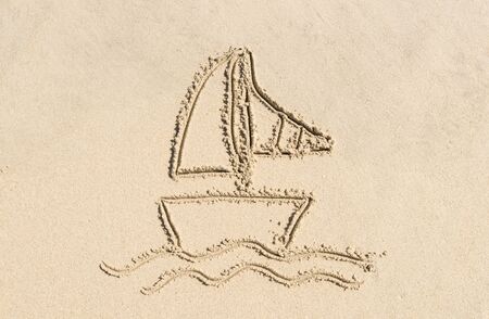 simple drawing in the sand on the beach of sailboat boatの写真素材
