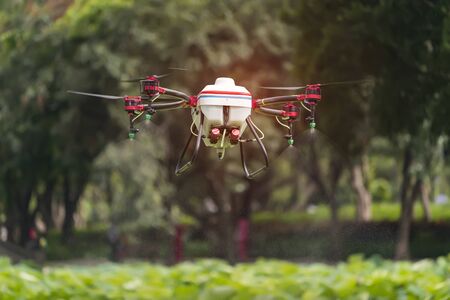 agriculture drone carry a tank of liquid fertilizer flying in the blue sky prepare to spray it in...