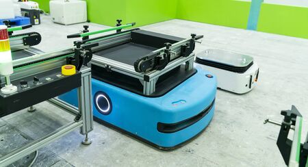 warehouse robot car carries cardboard box assembly in factoryの写真素材