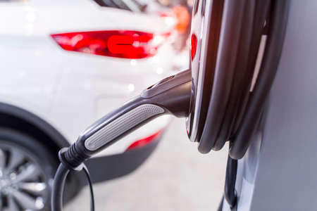 Electric car charging on parking lot with electric car charging station.