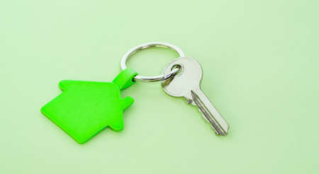 key chain with house symbol and keys on green background,Real estate concept