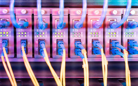 Fiber Optic cables connected to an optic ports and Network cables connected to portsの写真素材