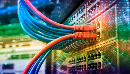 Server rack with blue and red internet patch cord cables connected to black patch panel in data server roomの写真素材