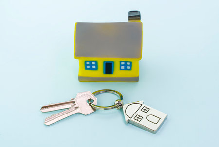 key chain with house symbol and keys on blue background, Real estate concept