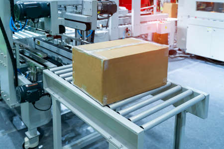 cardboard box of product packaging is moving on conveyor belt of automatic packing machine in the...