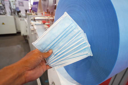 hand with mask with automatic machine for the manufacture of medical masks with nanofiber.