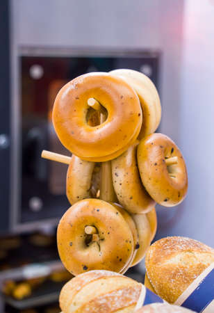 bagels hang on a stick in a row against a wooden latticeの写真素材