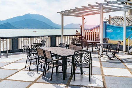 Empty tables on a terrace at a restaurant overlooking the sea and mountainsのeditorial素材