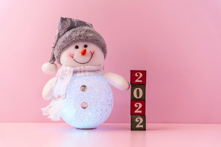 snowman with happy holiday and 2022 year concept with red blocks and text board on wooden backgroundの写真素材